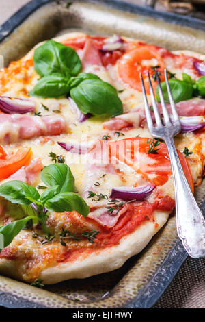 Hausgemachte Pizza mit Schinken und Tomaten, serviert mit Gabel auf Vintage Metalltablett. Stockfoto