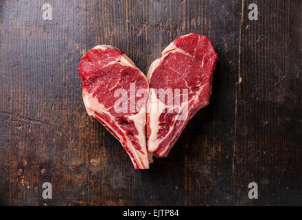 Herz Form rohes Fleisch Ribeye Steak Entrecote auf hölzernen Hintergrund Stockfoto