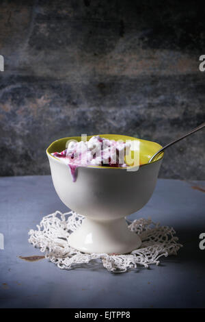 Weiße Keramik-Vase mit Vanilleeis, serviert mit Mix aus Beeren über grau Metall-Tisch Stockfoto