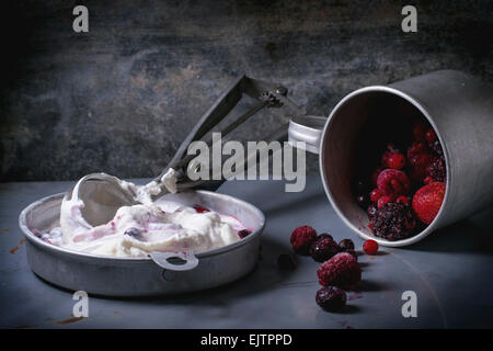 Aluminium-Platte mit Vanille-Eis und gefrorenen Beeren-Mix mit Metalllöffel über Metall-Tisch serviert. Stockfoto