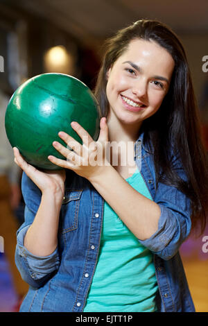 glückliche junge Frau mit Ball in Bowlingclub Stockfoto