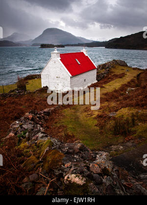 Eine weiße Landhaus aus Stein mit einem pulsierenden roten Dach am Ufer des Loch in die North West Highlands von Schottland. Stockfoto