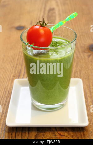 Grüne Spinat Smoothie und kleine rote Tomate, vertikale Stockfoto