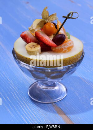 Galia Melone gefüllt mit Sommerfrüchten, gesunde Ernährung, blauer Hintergrund Stockfoto