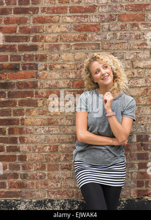 Porträt der jungen Frau vor Backsteinmauer Stockfoto