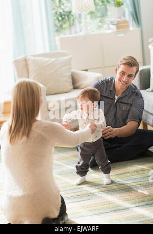 Glückliche Eltern helfen Söhnlein (2-3 Jahre) zu Fuß im Wohnzimmer Stockfoto