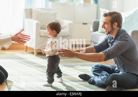Glückliche Eltern helfen Söhnlein (2-3 Jahre) zu Fuß im Wohnzimmer Stockfoto