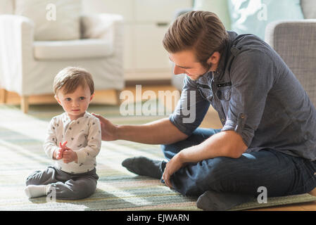 Vater sitzt am Boden mit kleinen Sohn (2-3 Jahre) Stockfoto