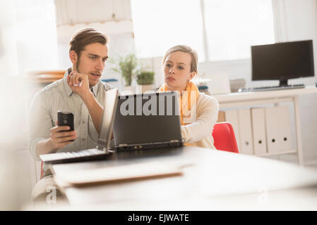 Junger Mann und Frau gemeinsam mit Laptop im Büro Stockfoto