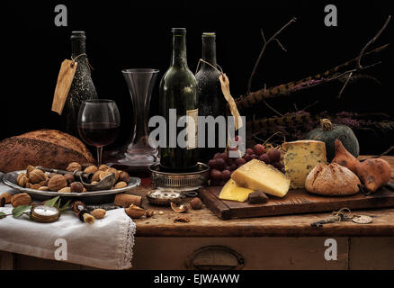 Stillleben mit Weinflaschen, Auswahl an Käse, Brot und Nüssen auf Holztisch, Studio gedreht Stockfoto