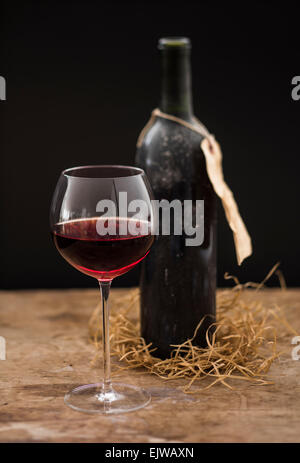 Stillleben mit Rotweinglas und Flasche auf Holztisch, Studio gedreht Stockfoto