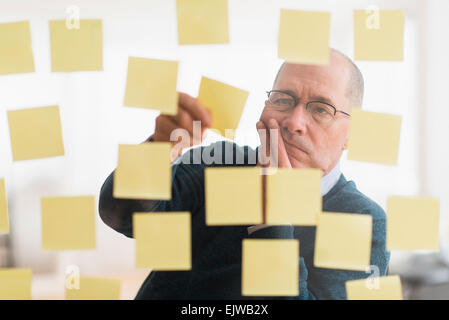 Vermittlung von Klebstoff Hinweise zur Glaswand Geschäftsmann Stockfoto