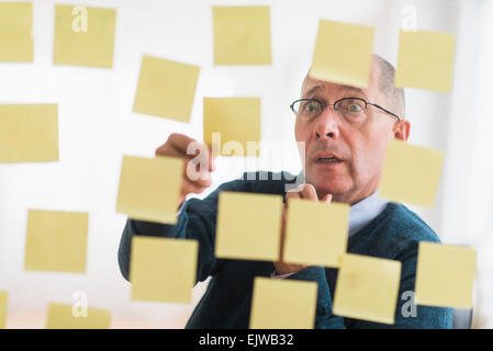 Überrascht, Geschäftsmann, Vermittlung von Klebstoff Hinweise zur Glaswand Stockfoto