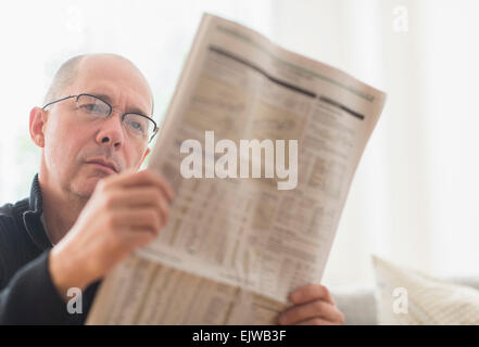 Reifer Mann liest Zeitung auf sofa Stockfoto