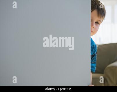 Junge (6-7) um Tür peering Stockfoto