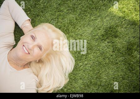 Ältere Frau liegt auf dem Rasen Stockfoto