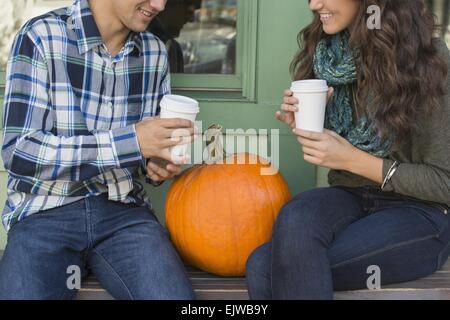 USA, Staat New York, New York City, Brooklyn, junges Paar sitzt auf der Bank mit Kaffeetassen Stockfoto