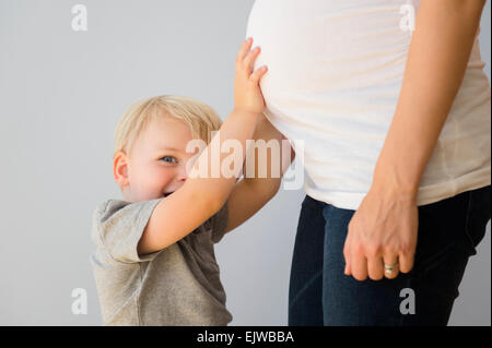 Porträt eines jungen (2-3) seine schwangere Mamas Bauch zu berühren Stockfoto