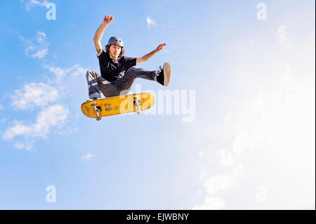 USA, Florida, West Palm Beach, Mann springt auf Skateboard gegen Himmel und Wolken Stockfoto