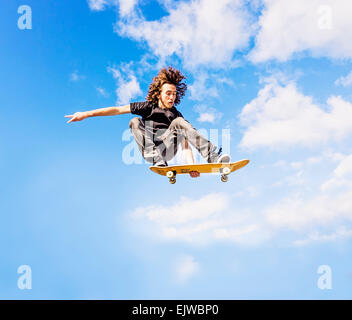 USA, Florida, West Palm Beach, Mann springt auf Skateboard gegen Himmel und Wolken Stockfoto