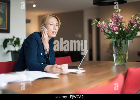 Frau am Telefon zu sprechen und sich Notizen macht Stockfoto