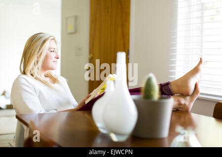 Junge Frau Lesebuch am Tisch Stockfoto