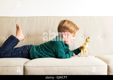 Jungen (2-3) spielt mit Spielzeug Dinosaurier auf sofa Stockfoto