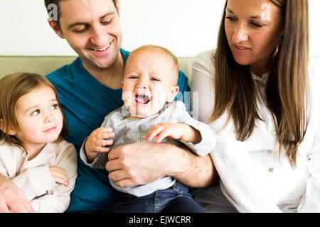 Familie mit zwei Kindern (2-3, 4-5) auf Sofa sitzen Stockfoto