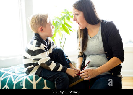 Mutter hilft Sohn (6-7) putting Schuh auf Stockfoto