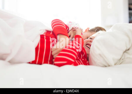 Bruder (6-7) und Schwester (4-5) Lachen im Bett Stockfoto