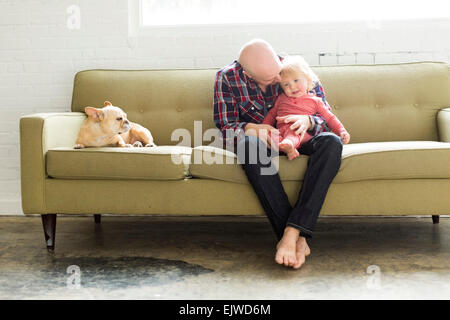 Vater sitzt auf dem Sofa umarmen Baby Sohn (2-3) Stockfoto
