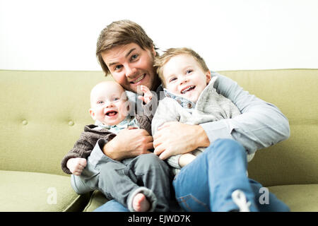 Vater umarmen zwei Söhne (6-11 Monate und 2-3 Jahre) Stockfoto