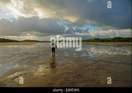 Irland, County Mayo, Clew Bay, Rückansicht des Mannes stehendes Wasser in Latex Stiefel, Wolken Himmel Stockfoto