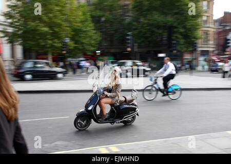 Eine Frau fährt einen Roller und einem Mann Reiten ein um Trafalgar Square, London, England. Stockfoto