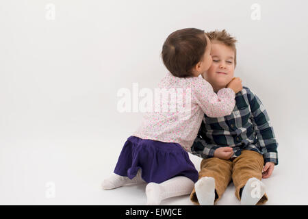 kleines Mädchen küssen ihr älteren Bruder auf die Wange, isoliert Stockfoto