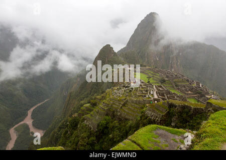 Peru, Machu Picchu.  Urubamba-Fluss, links unten, Huayna Picchu, Mitte rechts, gesehen vom Wachhaus, am frühen Morgen Wolken. Stockfoto