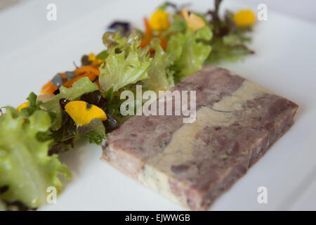 Geräucherter Schinken Hock und Gänseleber-Terrine mit hausgemachten Piccalilli und Salat garniert serviert auf einem weißen Teller. Stockfoto