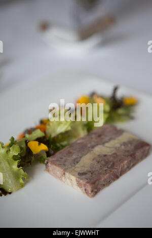 Geräucherter Schinken Hock und Gänseleber-Terrine mit hausgemachten Piccalilli und Salat garniert serviert auf einem weißen Teller. Stockfoto