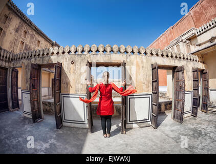 Frau im roten Kleid mit Schal Öffnen der Tür in Hawa Mahal, Rajasthan, Indien Stockfoto