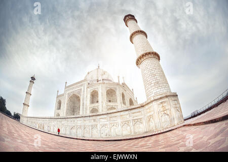 Frau in rot, die zu Fuß in der Nähe von Taj Mahal in dramatischen Himmel in Agra, Uttar Pradesh, Indien Stockfoto