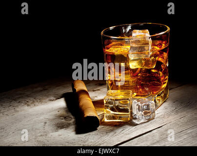 Glas im Alter von Whiskey mit Zigarre und Eiswürfeln auf Holztisch Stockfoto