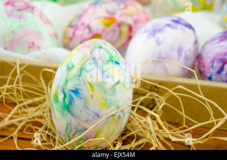 Handbemalte Ostereier auf einem Holztisch mit Stroh dekoriert Stockfoto