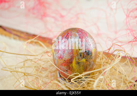 Handgemalte rötliche Easter Egg auf Holztisch in ein Nest gelegt Stockfoto