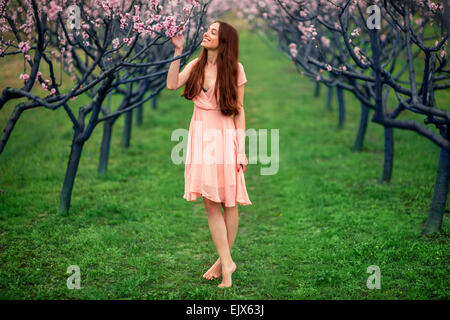 Frau genießen Frühling in der grünen Wiese mit blühenden Bäumen Stockfoto