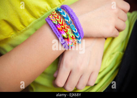 Kinderhände mit bunten Regenbogen Webstuhl Band GummiBracelets, Kinder trendige Mode-Accessoires Stockfoto