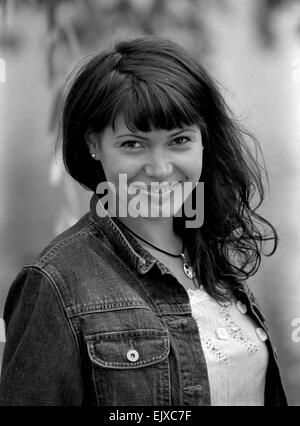 Schwarz-weiß-Porträt einer lächelnden jungen Frau in Jeans Jacke und mit rundem Anhänger. Stockfoto