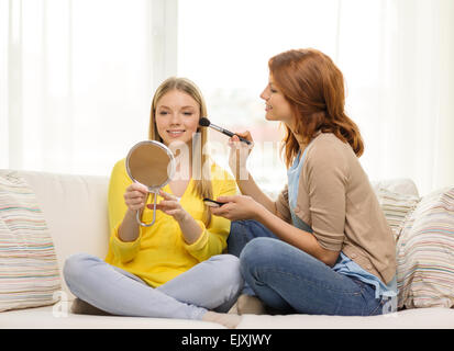 zwei lächelnde Mädchen im Teenageralter Anwendung Make-up zu Hause Stockfoto