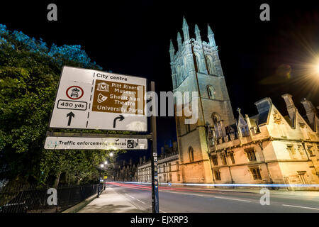 Ein Schild für Stadtzentrum von Oxford und Points of Interest hinter denen ist Magdalen College der Oxford University in der Nacht zu sehen. Stockfoto