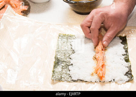 Hände, die kochen Sushi mit Lachs und nori Stockfoto