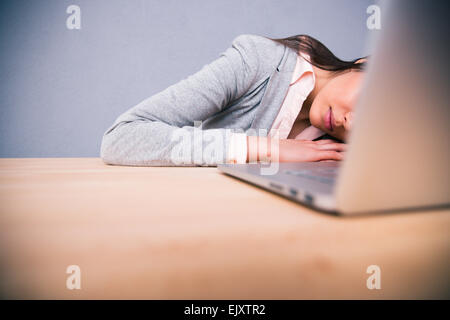 Niedliche Business-Frau mit Laptop auf dem Tisch schlafen Stockfoto